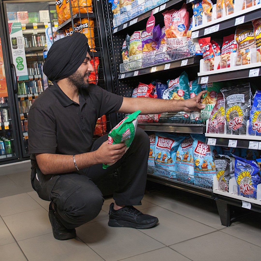 A convenience store employee restocking a shelf