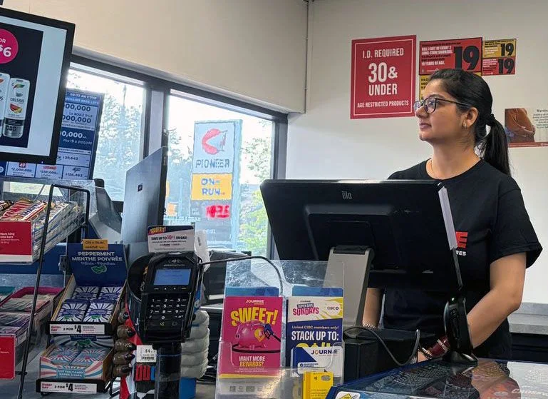 Une employée de dépanneur souriante derrière la caisse